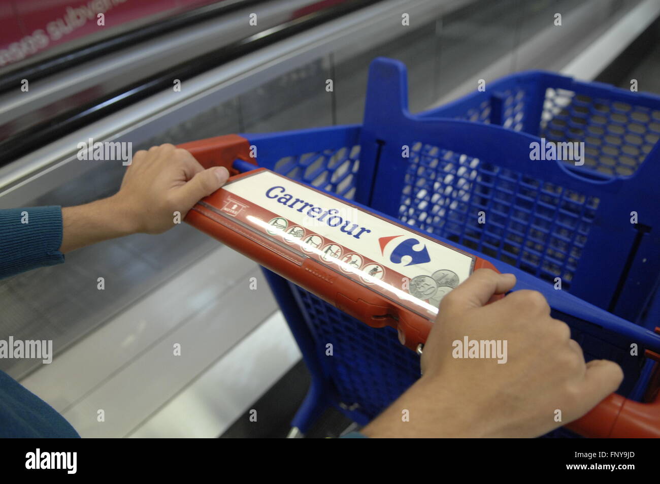 Carrefour carrello essendo spinto in Escalator Foto Stock