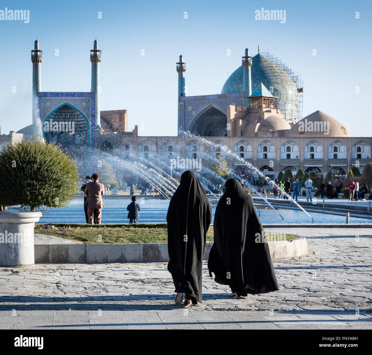 Rivestito di chador donne a Imam Piazza con fontane e la cupola e i minareti della Moschea Imam in background. Isfahan, Iran Foto Stock