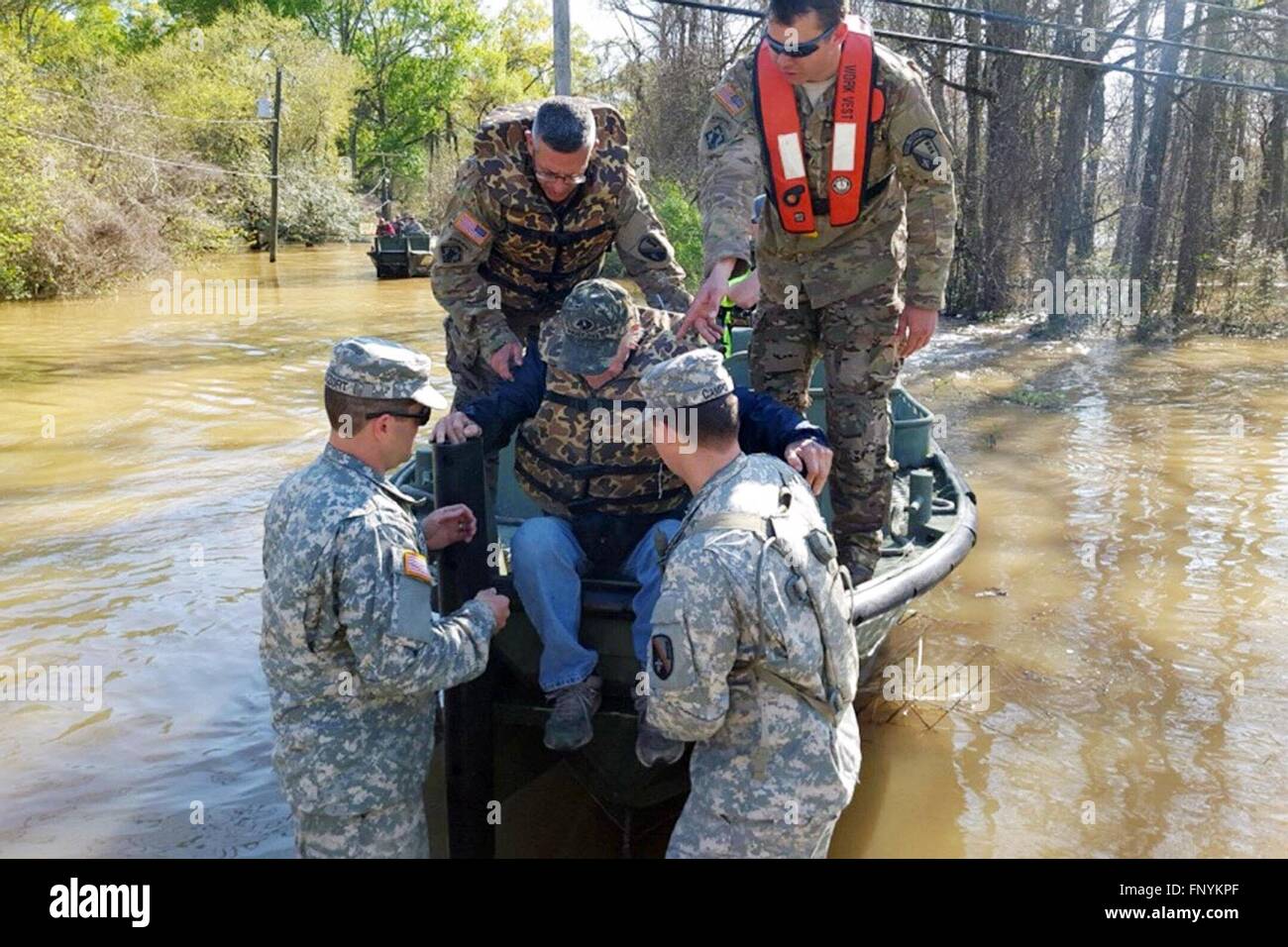 Louisiana National Guardmen assistere i residenti su una barca per sfuggire alla acque alluvionali dalle loro case sommerse lungo la perla e fiumi Foglia dopo record di tempeste di pioggia di dumping attraverso il profondo sud Marzo 13, 2016 in Ponchatoula, Louisiana. Foto Stock