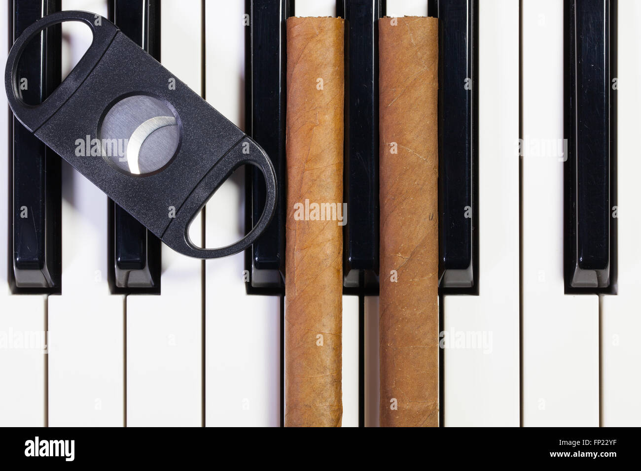 Dettaglio della tastiera di pianoforte e sigari di lusso Foto Stock
