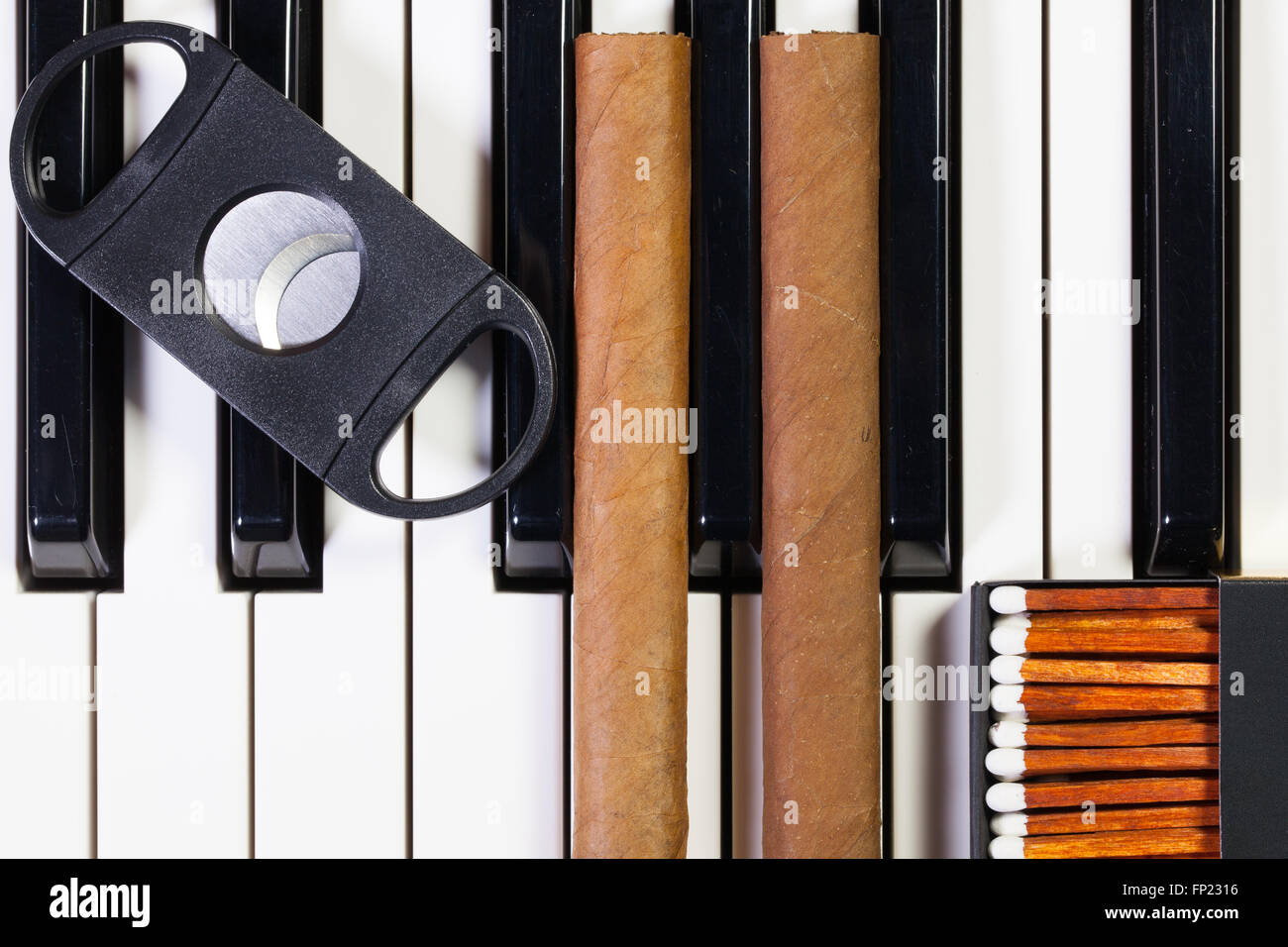 Dettaglio della tastiera di pianoforte e sigari di lusso Foto Stock