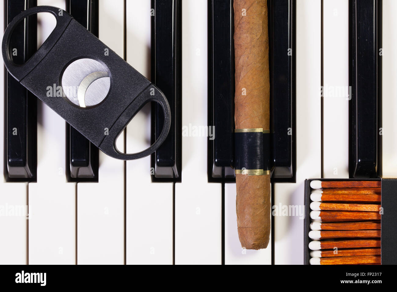 Dettaglio della tastiera di pianoforte e sigari di lusso Foto Stock