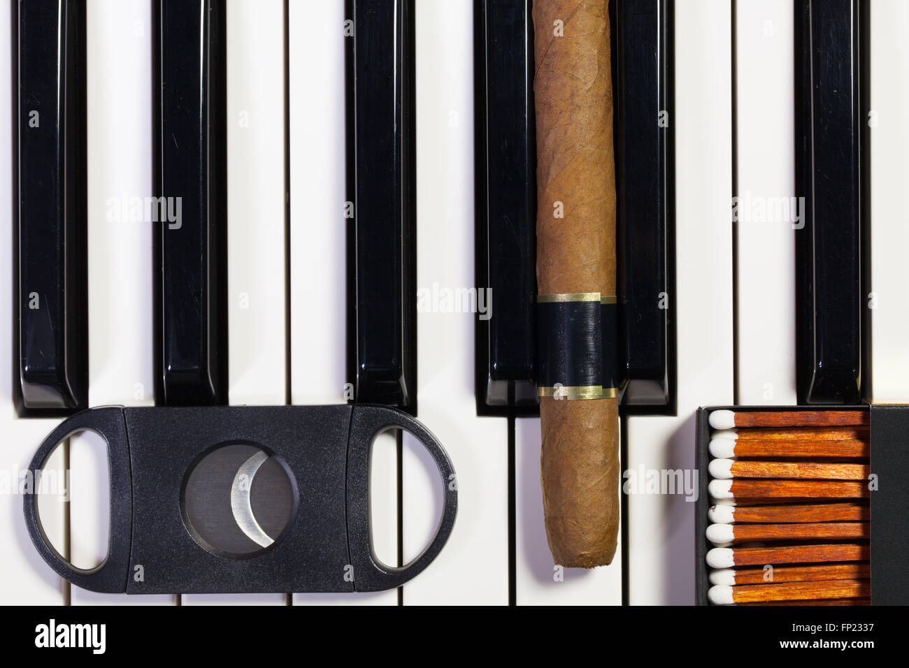 Dettaglio della tastiera di pianoforte e sigari di lusso Foto Stock