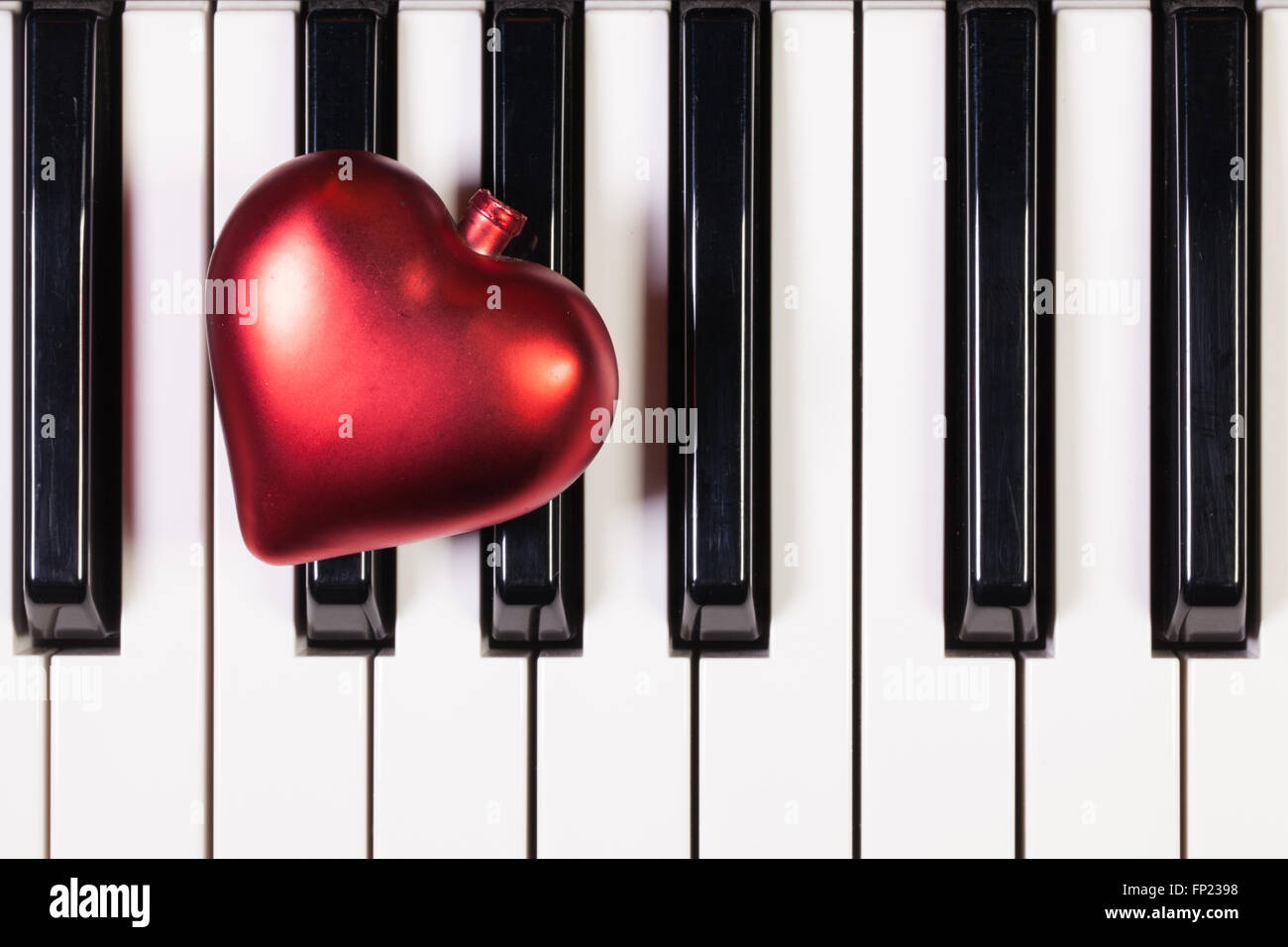 Dettaglio della tastiera di pianoforte e cuore rosso Foto Stock