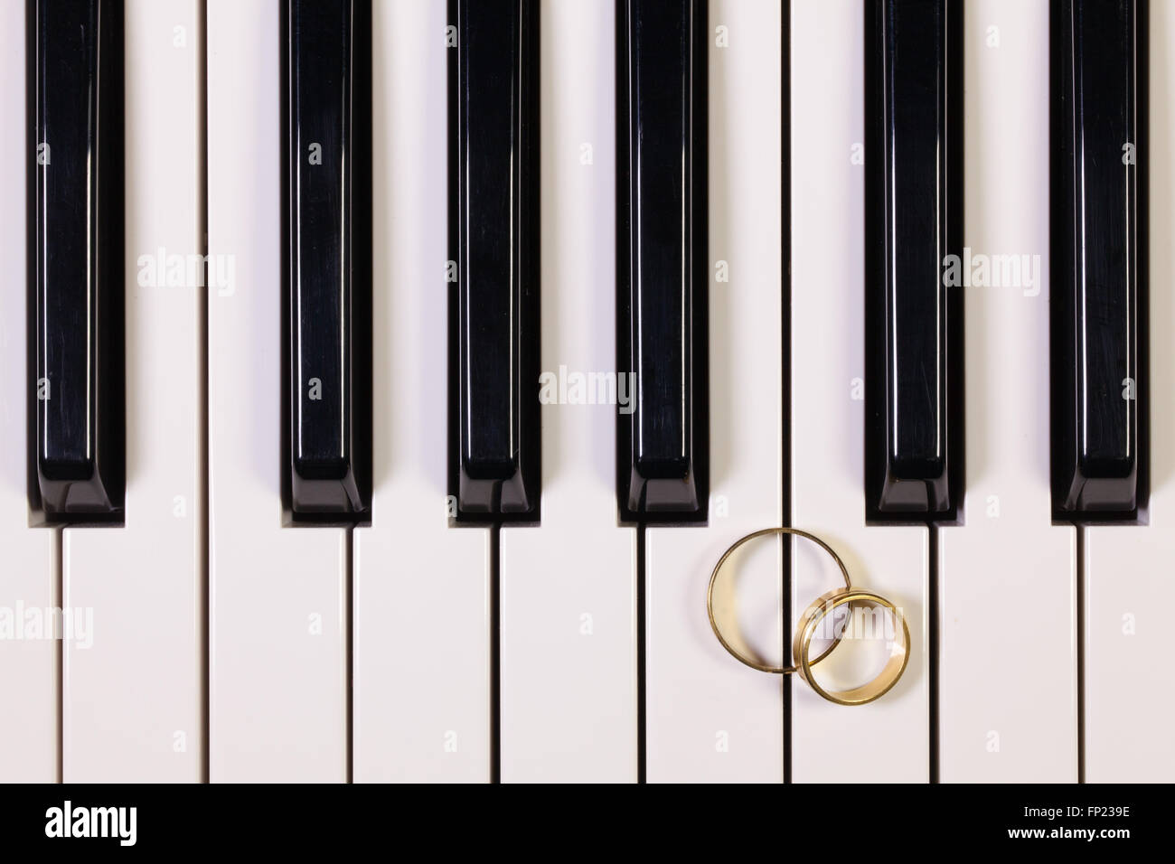 Dettaglio della tastiera di pianoforte e gli anelli di nozze Foto Stock