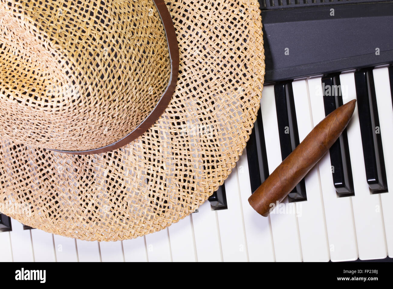 Dettaglio della tastiera di pianoforte,cappello di paglia e sigari di lusso Foto Stock