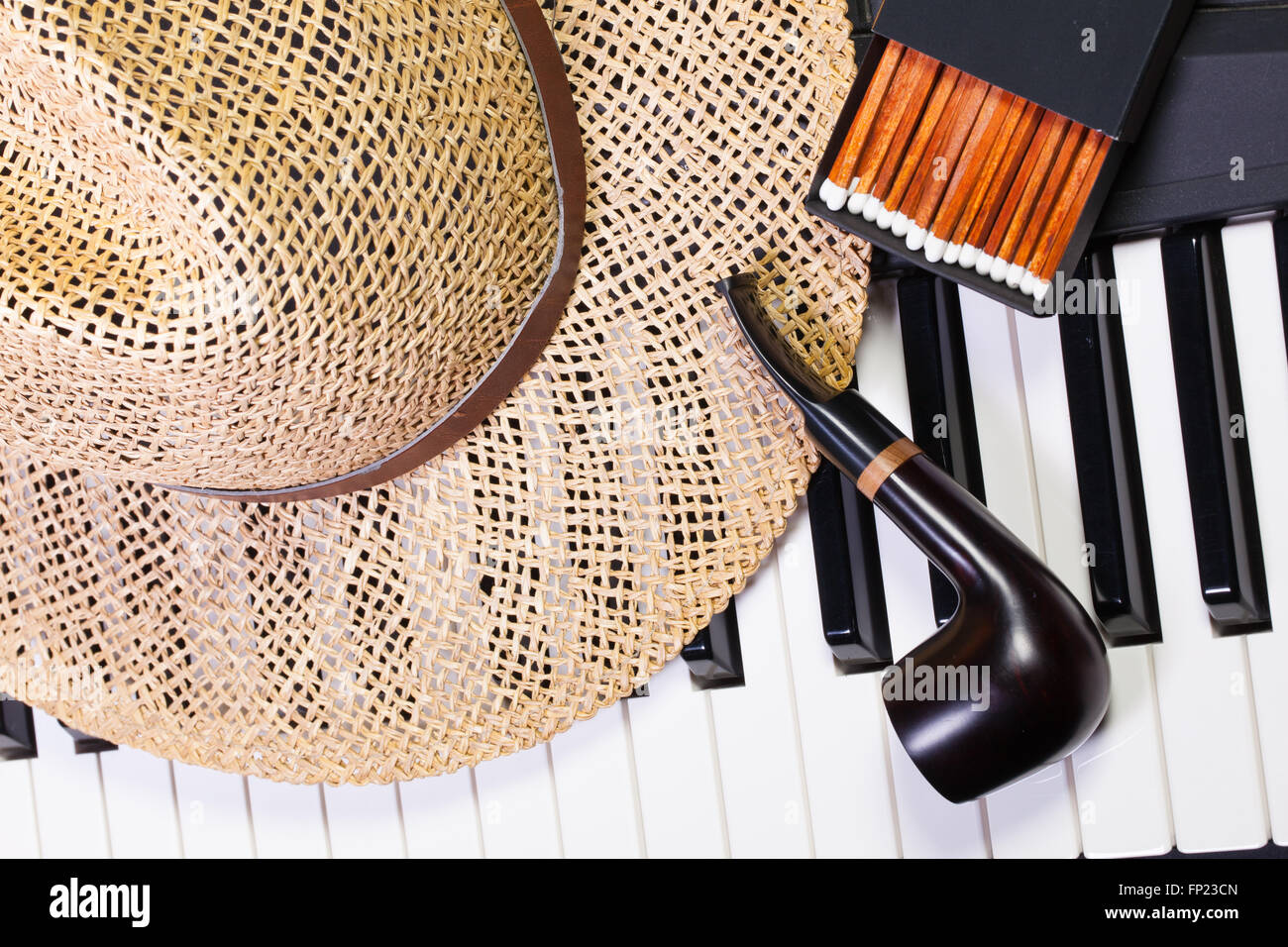 Dettaglio della tastiera di pianoforte,cappello di paglia e tubazione di lusso Foto Stock