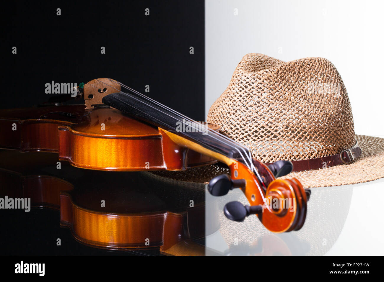 Vecchio violino e cappello di paglia isolato in bianco e nero e sfondo scrivania in vetro Foto Stock