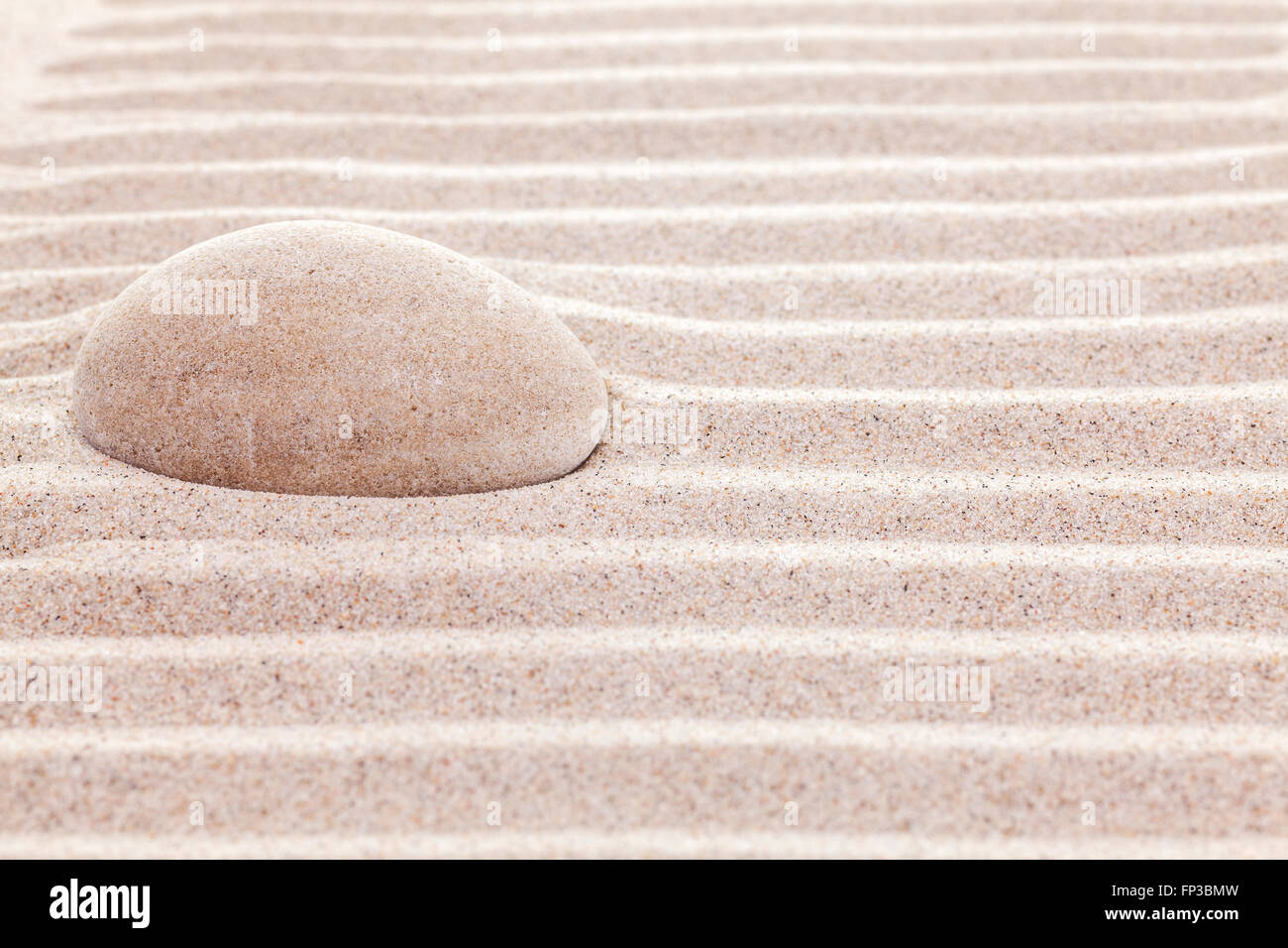 La pietra in sabbia, spa o sfondo spirituale. Foto Stock