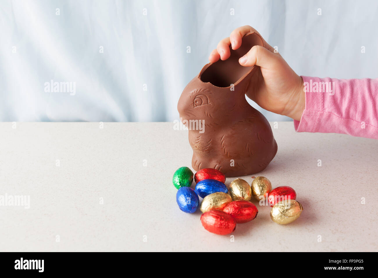 Bambino di rottura a mano un orecchio off cioccolato coniglietto di pasqua con copia spazio. Foto Stock