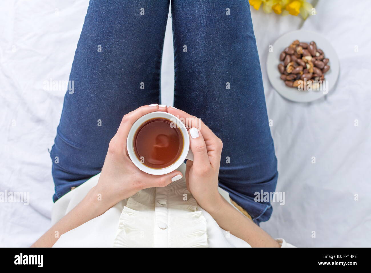Donna con una tazza di tè prima di lavorare a letto Foto Stock