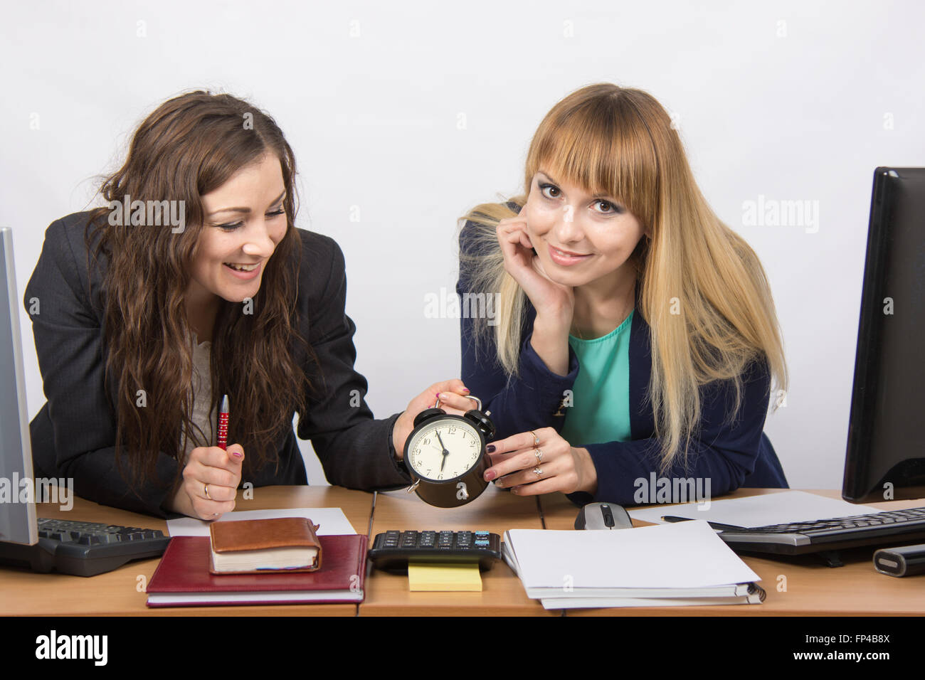 Due ragazze in ufficio felicemente in attesa per la fine del giorno lavorativo Foto Stock