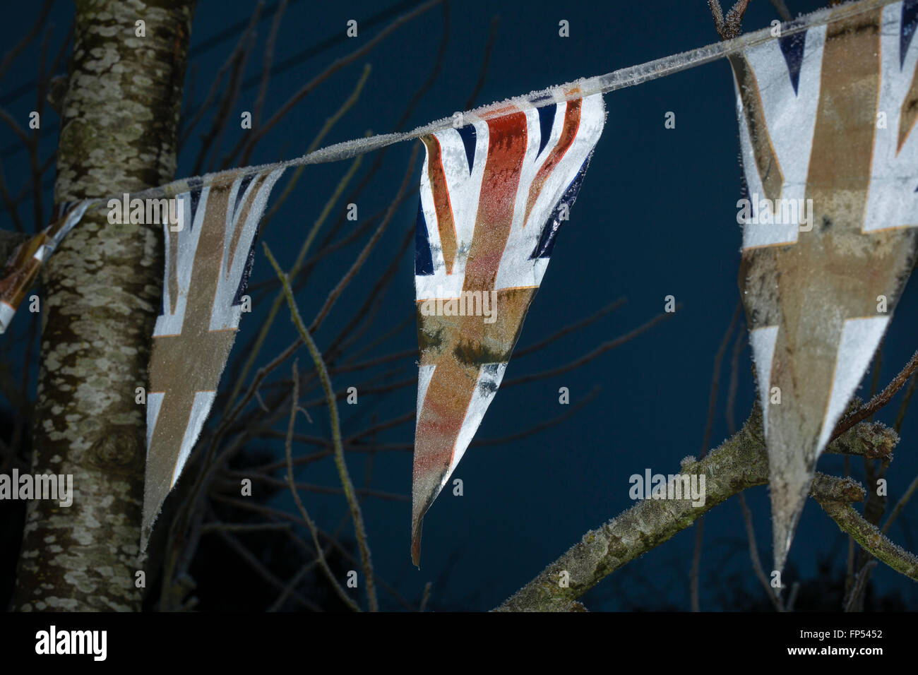 Vecchio sbiadito bunting con Union Jack flag onda in inverno i venti sbiadito adn vecchio appeso a un albero. Foto Stock