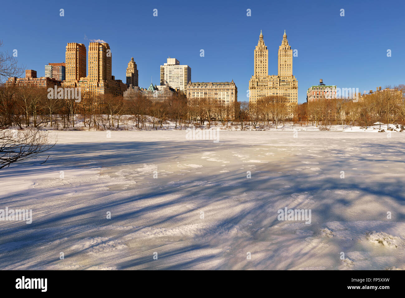 Alba sul congelate, coperta di neve Central Park lago con vista dell'Upper West Side di edifici, Manhattan. La città di New York Foto Stock