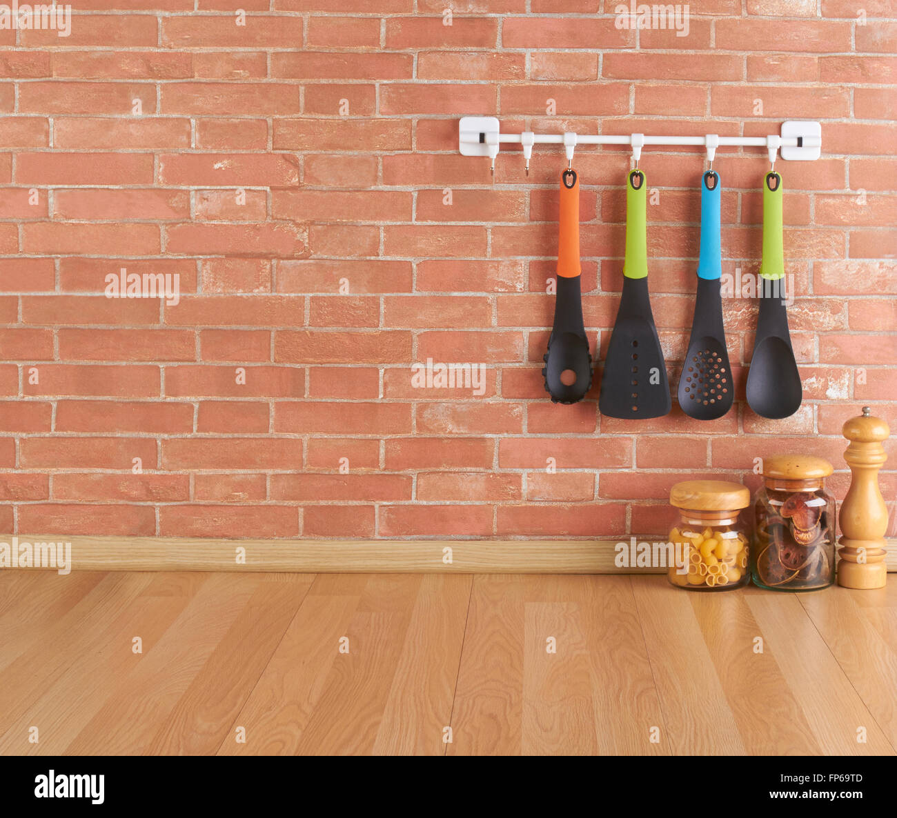 Spazio vuoto sul bancone della cucina con utensili su ganci contro un muro di mattoni Foto Stock