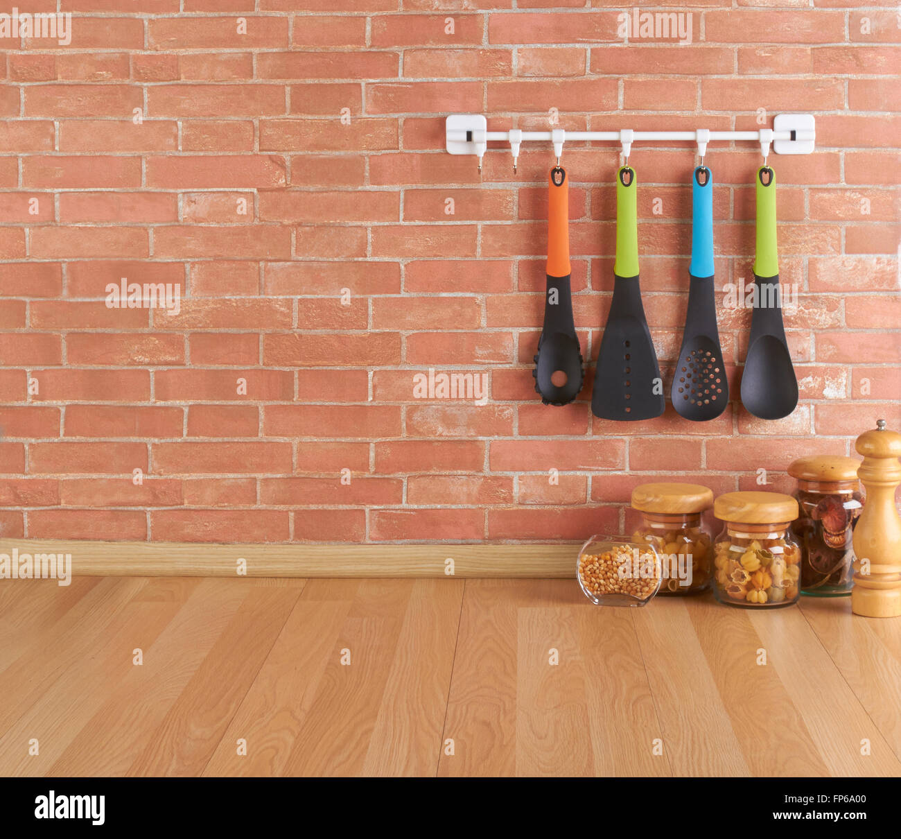 Spazio vuoto sul bancone della cucina con utensili su ganci contro un muro di mattoni Foto Stock