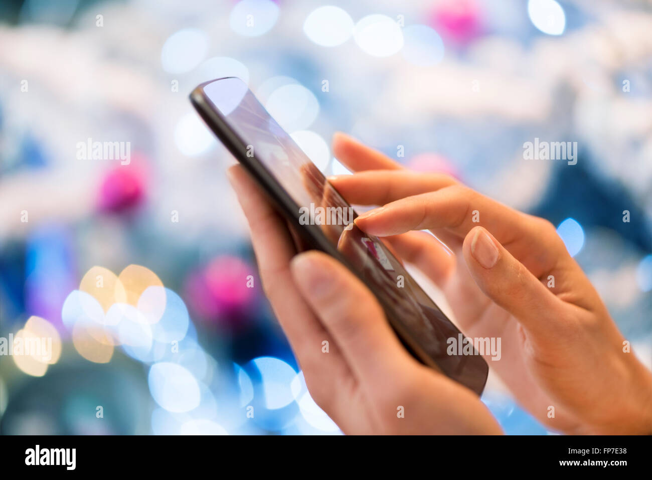 Donna che utilizza il suo telefono cellulare a casa. Boke albero di Natale sfondo; App,sms,chat,messaggio,e-mail,invio messaggi Foto Stock