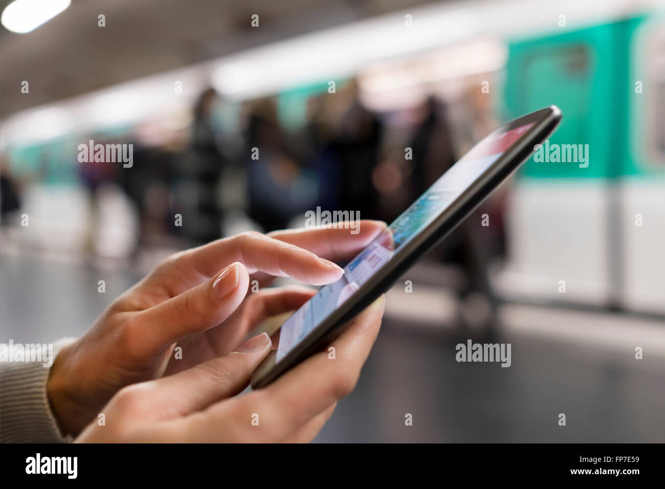 Donna che utilizza il suo telefono mobile sulla piattaforma della stazione della metropolitana. App, sms, messaggio, e-mail, messaggi di testo Foto Stock