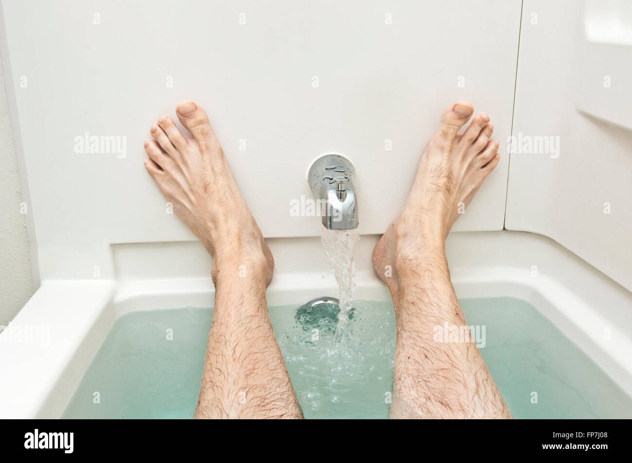 Vasca da bagno con acqua in esecuzione e uomo di piedi Foto stock - Alamy