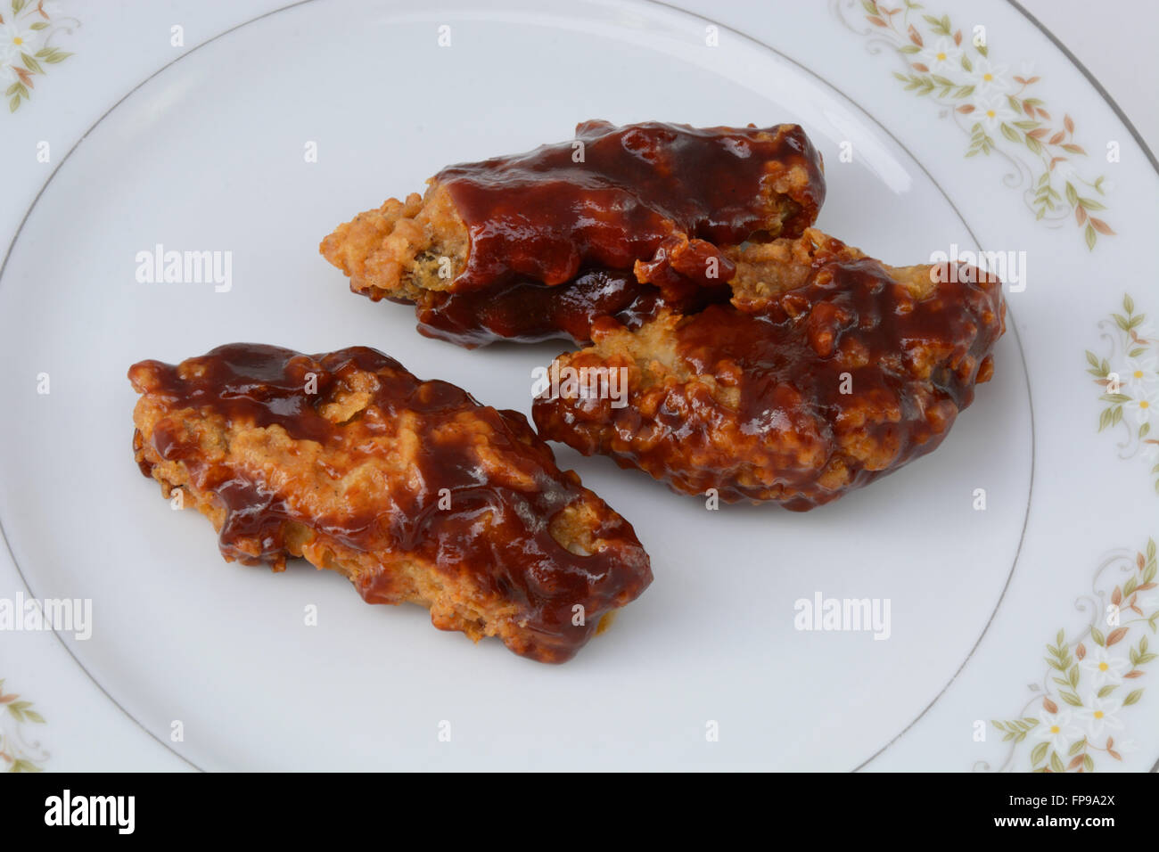 Ali di pollo con salsa barbecue sulla piastra Foto Stock