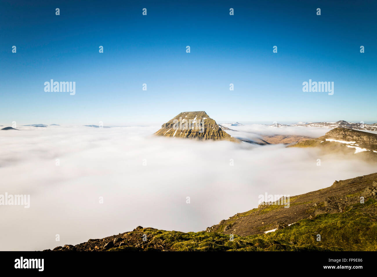 Chiara picchi di montagna e il cielo blu con nuvole basse che copre la terra e il mare. Isole Faerøer, Danimarca,l'Europa. Esposizione lunga Foto Stock