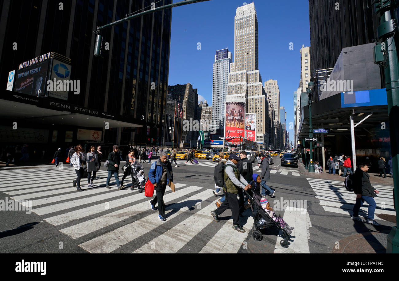 Pedoni che attraversano la strada a midtown Manhattan con Penn Station Madison Square Garden sulla sinistra. La città di New York, Stati Uniti d'America Foto Stock