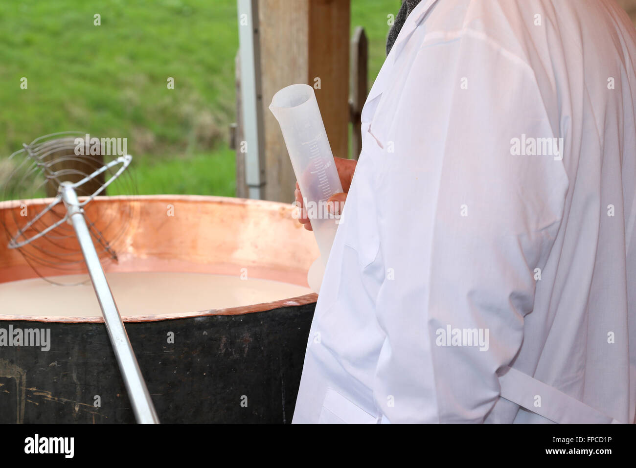 Casaro con camici e tubo di plastica per versare il caglio al latte Foto Stock