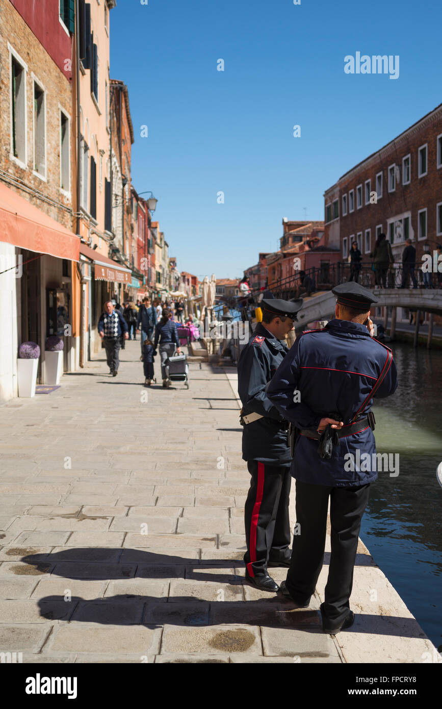 Uno dei poliziotti in attesa e uno dei poliziotti facendo una chiamata in una luminosa mattina di primavera in un canale sulla isola di Murano,Venezia,Italia Foto Stock