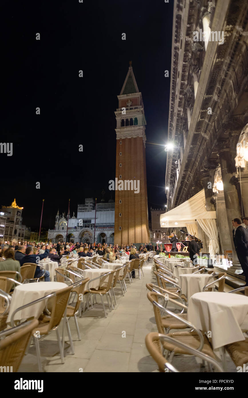 La gente ascolta una piccola orchestra in un concerto serale presso il cafe' "Caffe Florian' sulla piazza San Marco a Venezia Foto Stock
