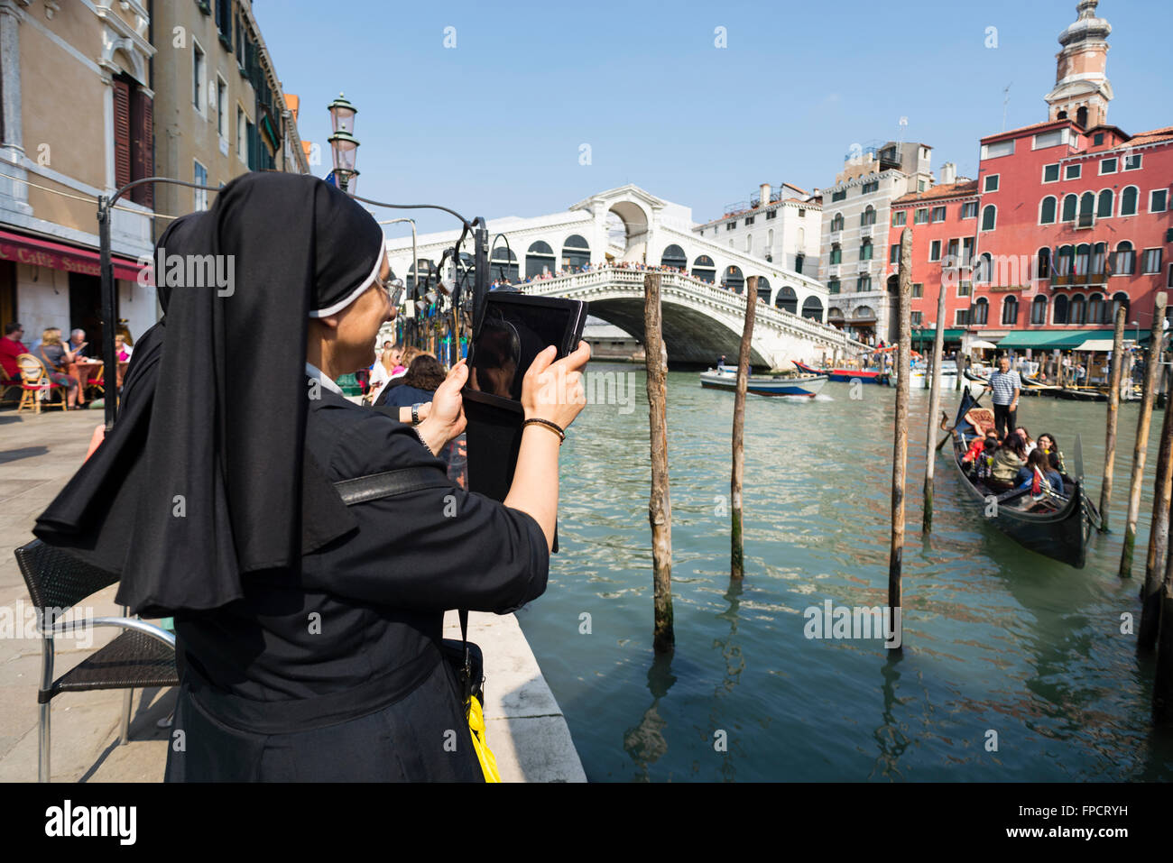 Suora cattolica di scattare le foto con un computer tablet di una gondola con i passeggeri sul Canal Grande al Ponte di Rialto, Venezia Foto Stock
