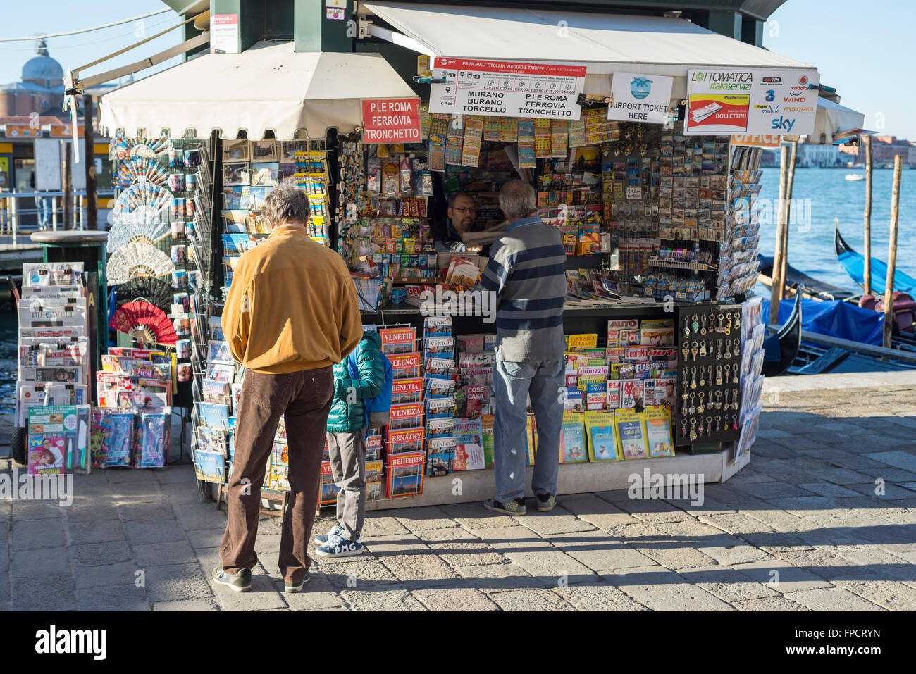 Tre clienti guardando e acquisto di carte su un tipico giornale italiano di stand a Venezia Foto Stock