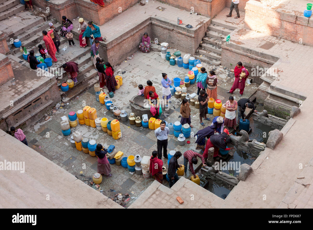 Il Nepal, Patan. Le donne e gli uomini schierati al manga Hiti, una pubblica fontana di acqua che serve i residenti che non hanno acqua corrente. Foto Stock