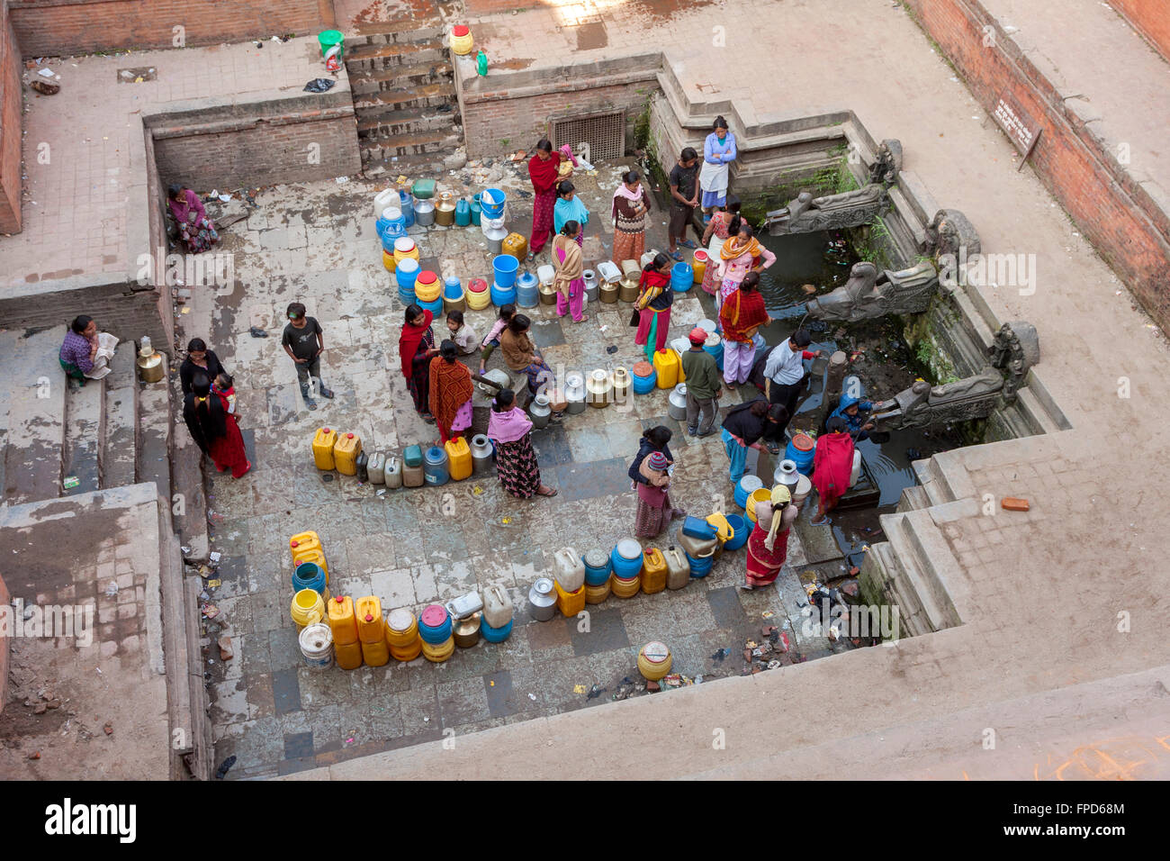 Il Nepal, Patan. Le donne e gli uomini schierati al manga Hiti, una pubblica fontana di acqua che serve i residenti che non hanno acqua corrente. Foto Stock