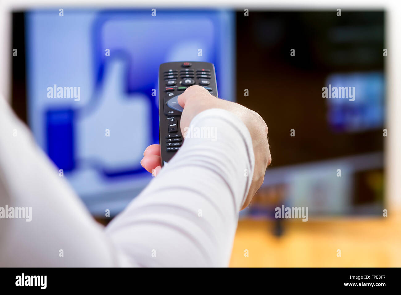 Closeup donna sulla mano che tiene il telecomando e navigare su internet con la televisione. Focus sul telecomando. Foto Stock