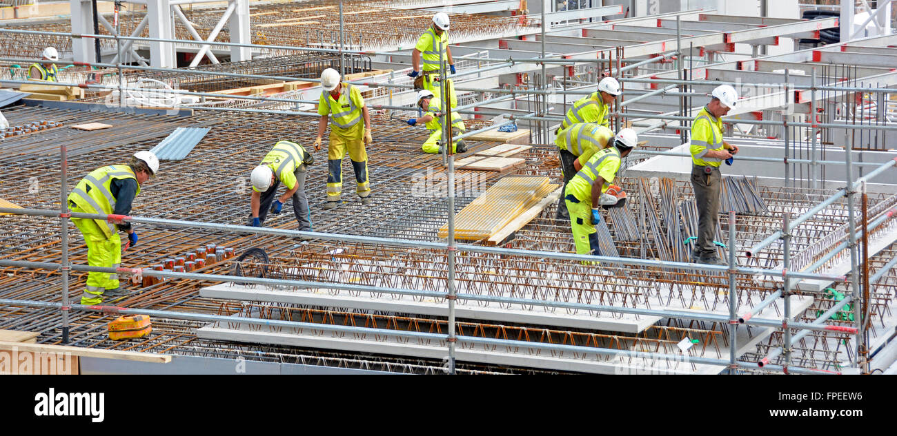 Lavoratori del cantiere impegnati a lavorare insieme per fissare rinforzi in acciaio per piani sospesi in cemento, alti appartamenti Londra, Inghilterra, Regno Unito Foto Stock