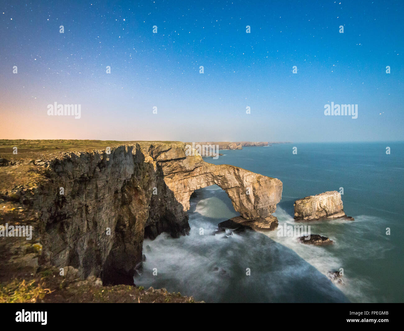 Un vicino alla luna piena illumina il Ponte Verde del Galles e il South Pembrokeshire litorale Foto Stock
