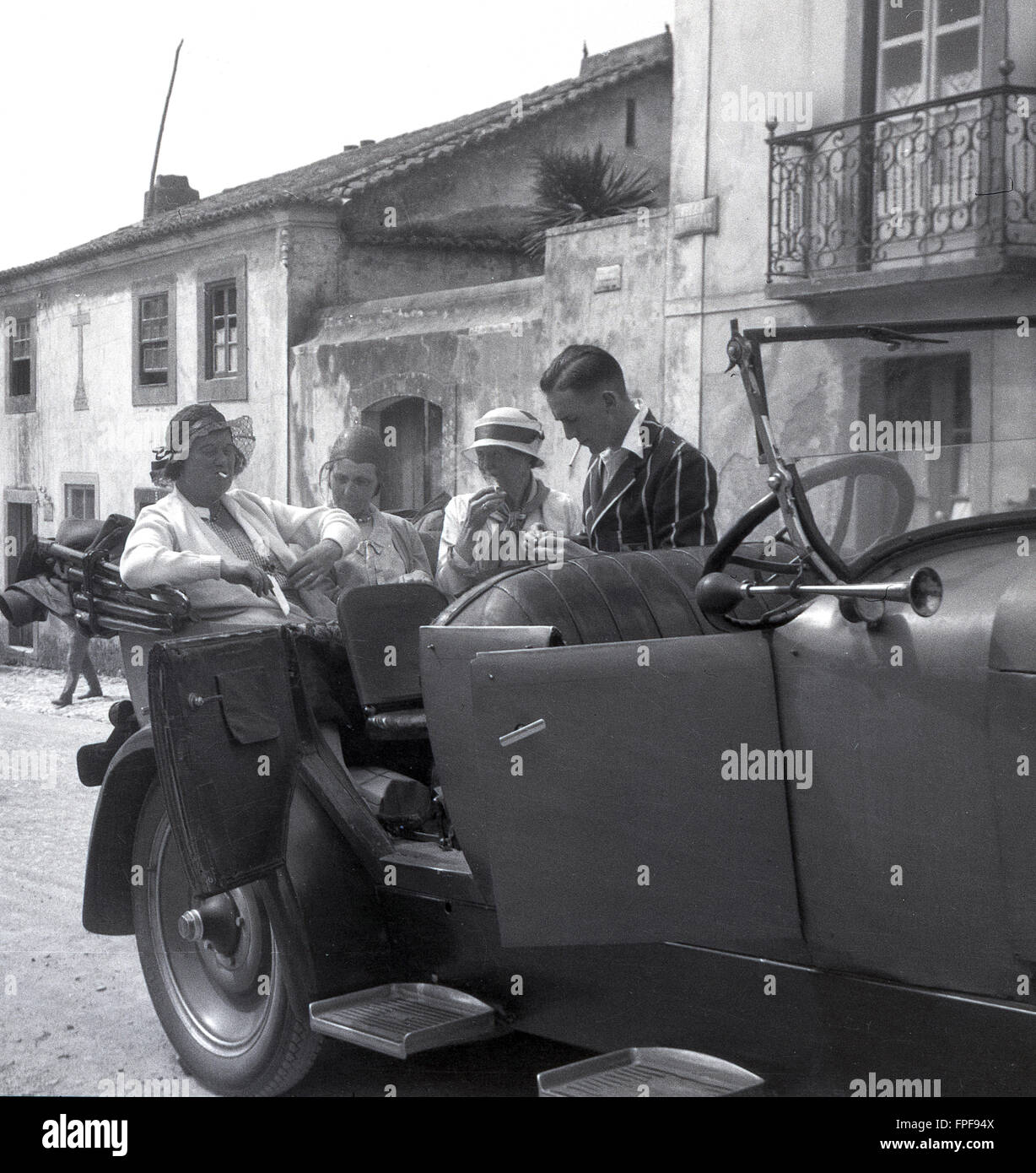 1930s storico, persone su un Grand Tour Europeo in un aperto e rabboccato auto godendo di una sigaretta. Foto Stock