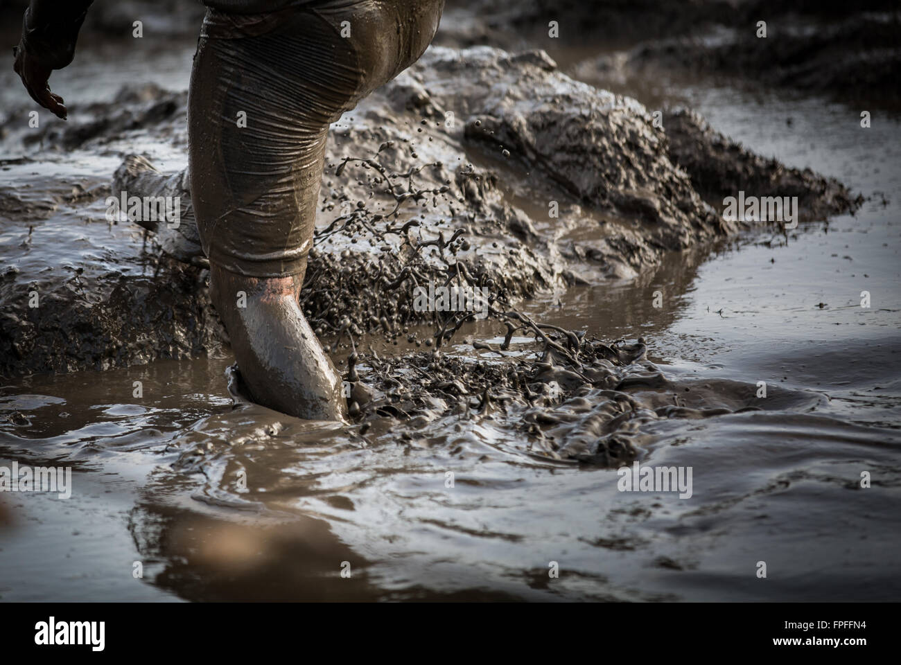 Deep acqua fangosa con piedini schizzi e arrampicata fuori dal fango in una gara Foto Stock