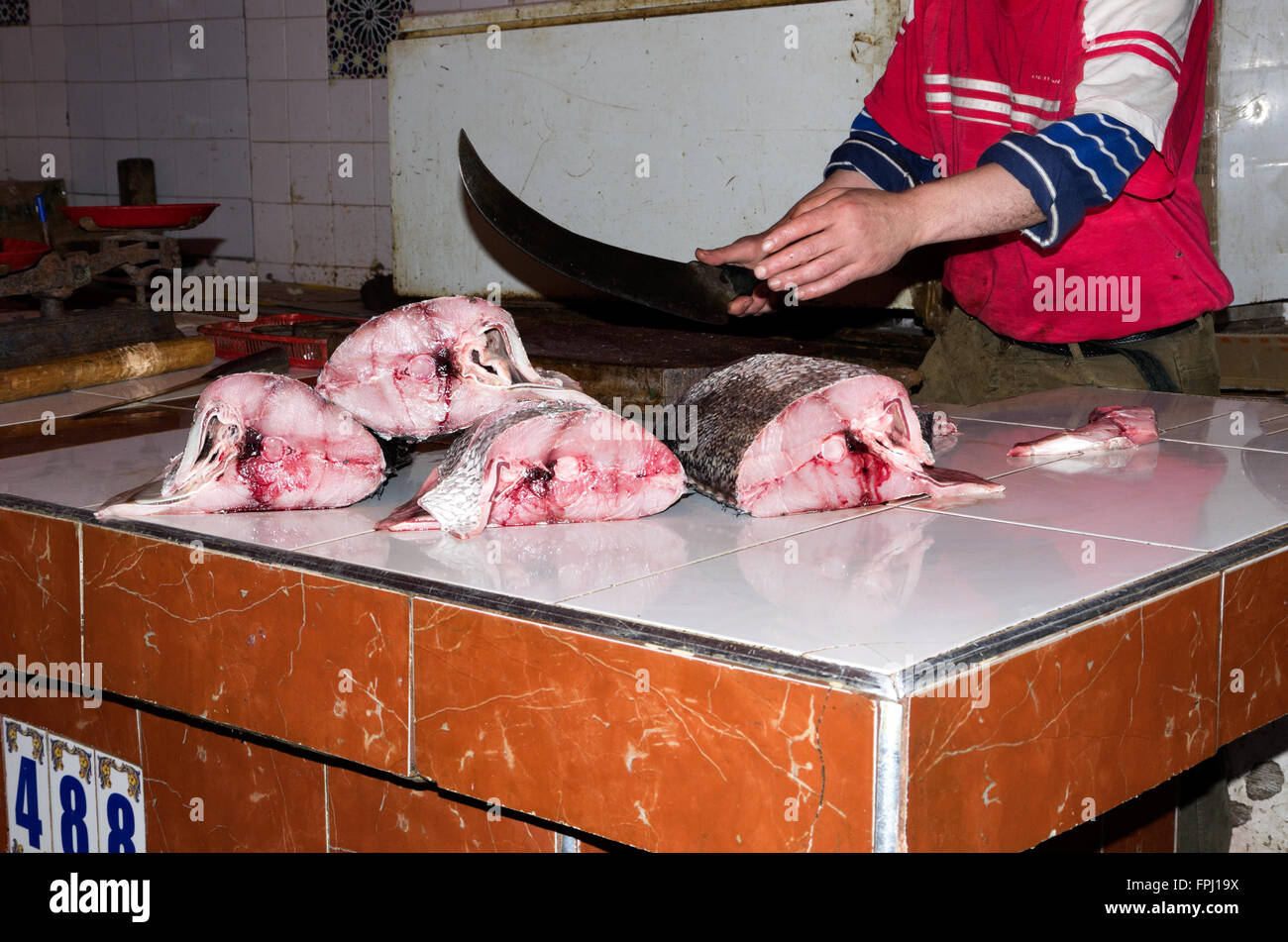 Fish monger tagli grandi pezzi di tonno con coltello molto affilato nel souk Foto Stock