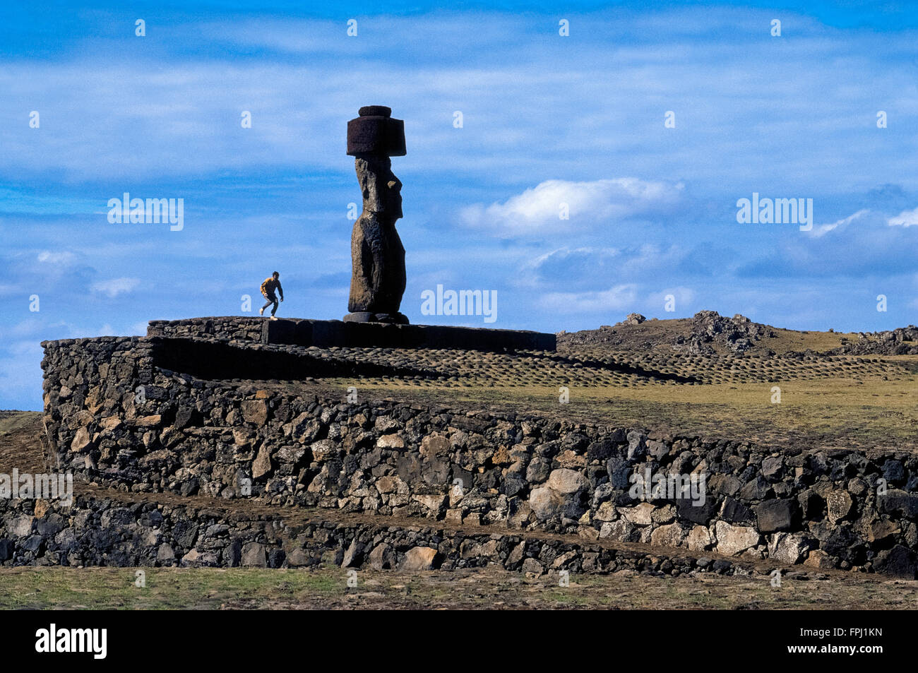 Un visitatore viene sopraffatte da uno dei 887 statue monumentali (moai) creati dai primi Rapa Nui popolazione polinesiana sulla remota Isola di Pasqua nell'Oceano Pacifico. Il gigante di pietra figure decorare questa antica isola vulcanica che ora è un territorio del Cile e situato a 2.300 miglia (3.700 chilometri) ad ovest del Sud America. Le imponenti sculture primitive sono sparsi in un grande cileno parco nazionale che è un sito Patrimonio Mondiale dell'UNESCO. Foto Stock