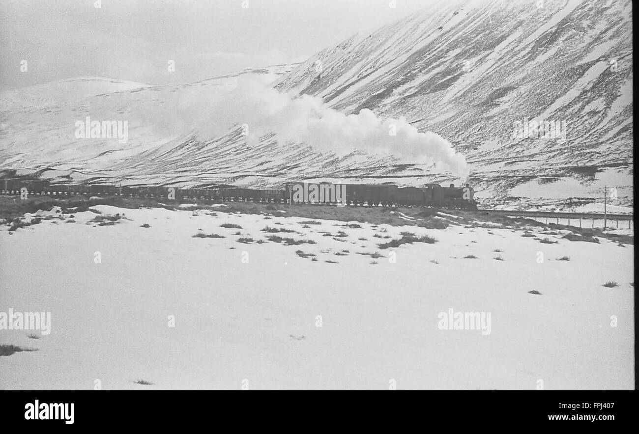 Highland surriscaldato ferroviaria Loch 4-4-0 traina un treno di merci su Drumochter passano nella neve in LMS giorni Foto Stock