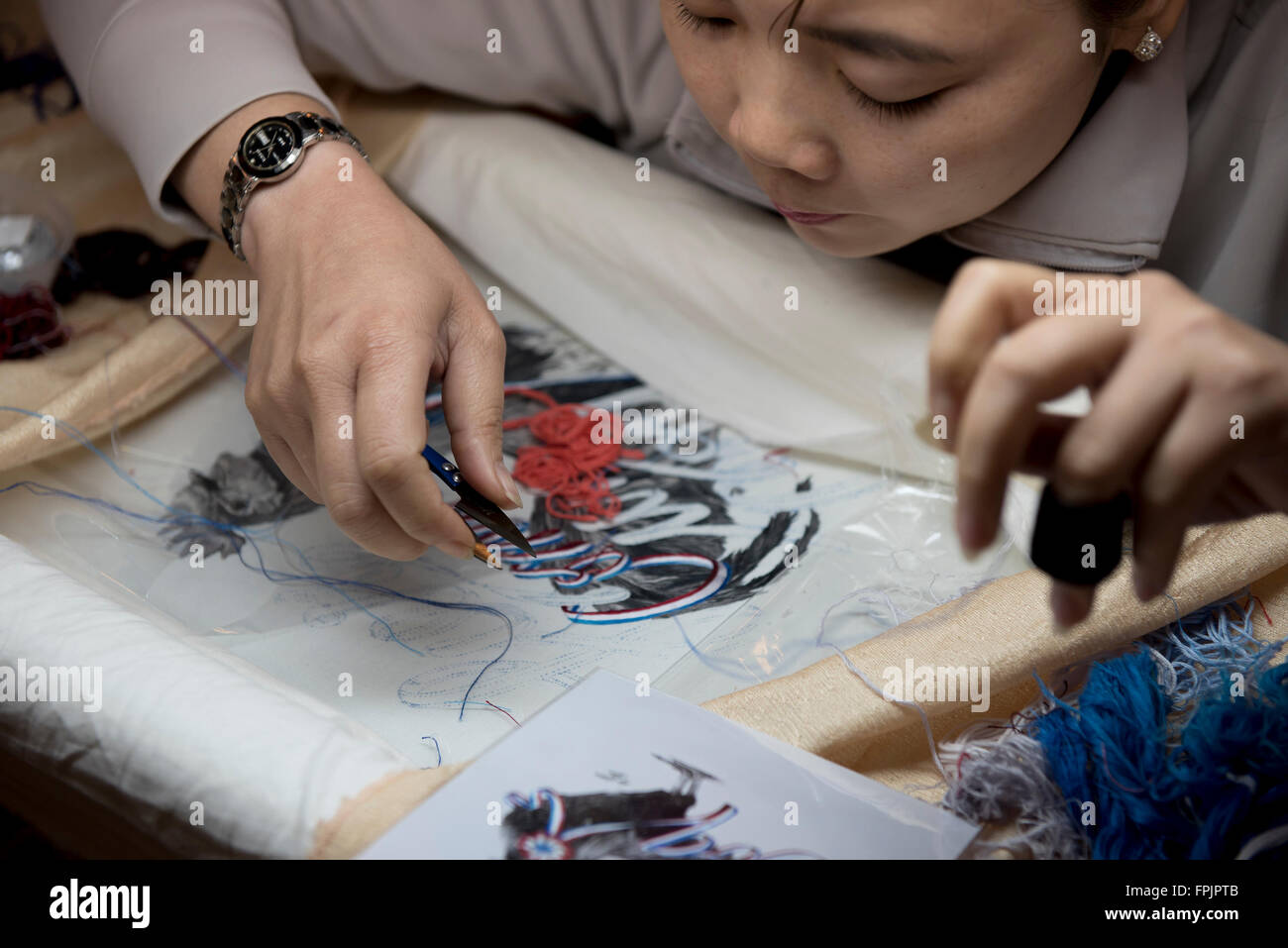 Hoi An, Vietnam lavoratore di sesso femminile che ricamare una foto con filo di seta. Il lavoro è ad alta intensità di manodopera e accurato Foto Stock