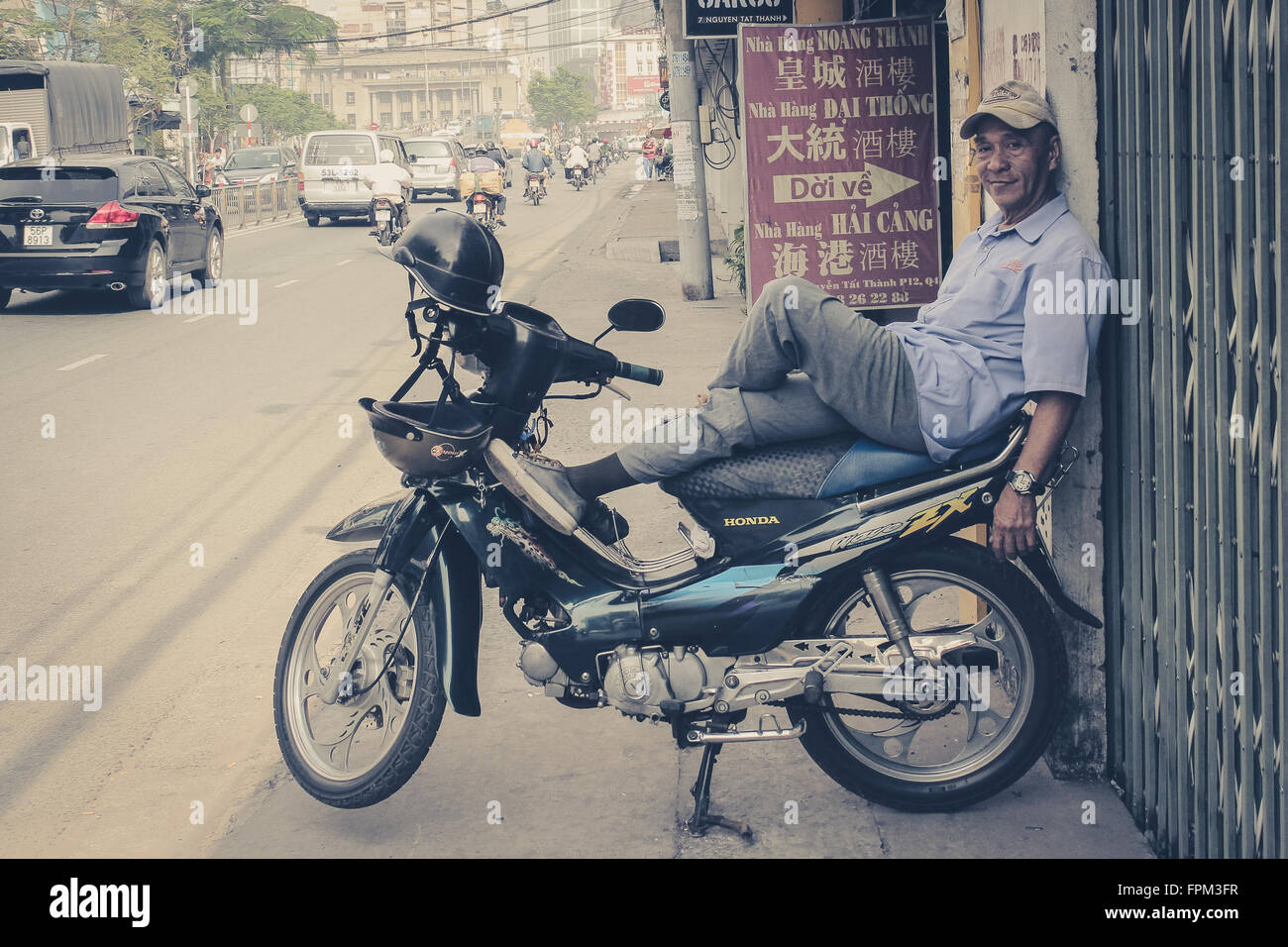 A Saigon, Vietnam - Gennaio 17, 2014: Ritratto di un uomo rilassante sul suo scooter / moto. Saigon è conosciuta come città in moto. Foto Stock