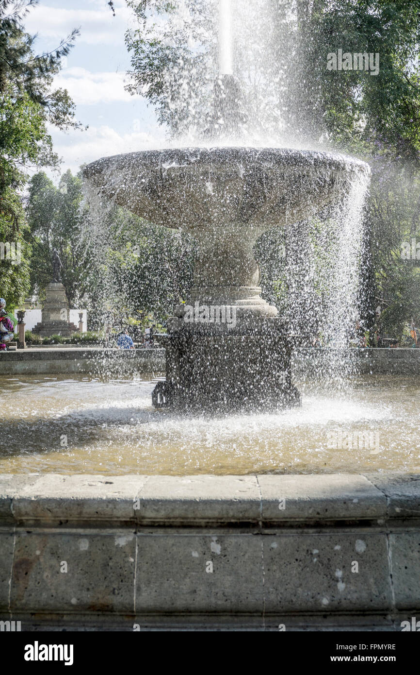 Fontana in primavera nello Llano Park con un grande lavabo in pietra & wind panna spray da getto d'acqua arruffamento superficie di acqua Oaxaca Foto Stock