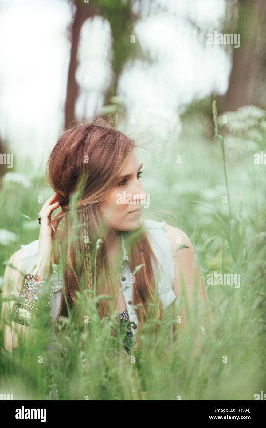 Donna seduta nel prato, guardando al lato Foto Stock