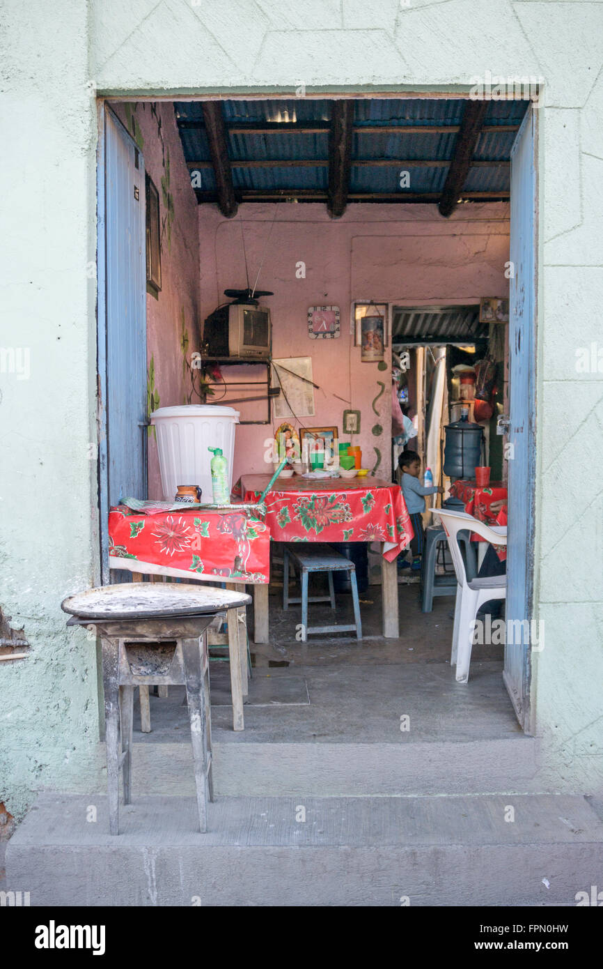 Vecchia stufa a carbone sulla porta stoop al di fuori di una sala aperta con pochi tavoli coperti in tela cerata Natale indica piccole taco shop Foto Stock