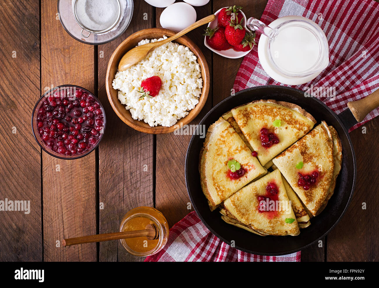 Golden frittelle con marmellata di mirtilli e miele in uno stile rustico. Vista superiore Foto Stock