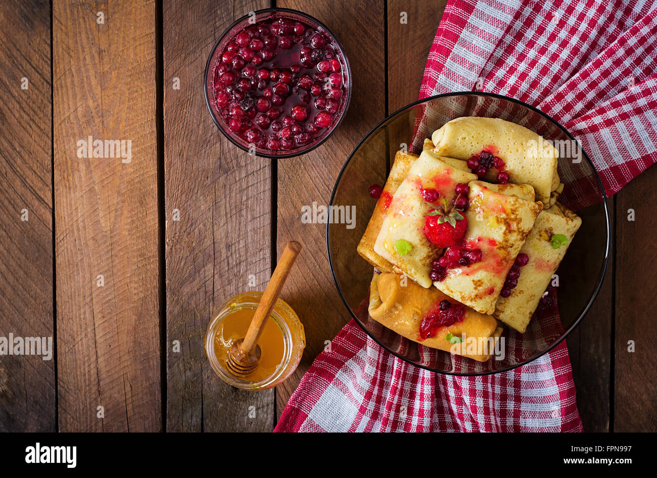 Golden frittelle con marmellata di mirtilli e miele in uno stile rustico. Vista superiore Foto Stock