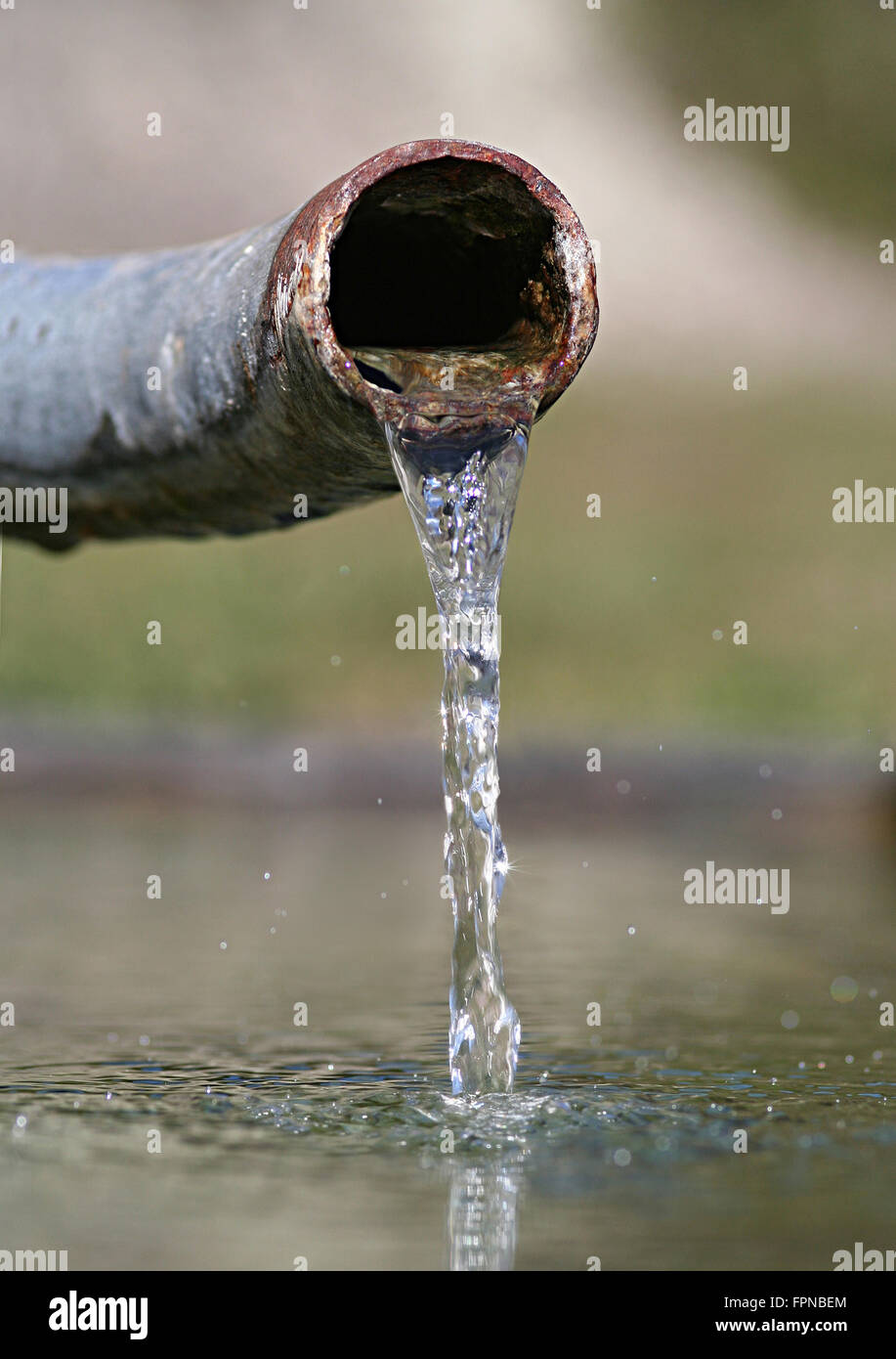 Acqua cristallina emergente dalla rusty vecchia tubazione. Simbolo per acqua limpida e nazione in via di sviluppo e la distribuzione di acqua ecc.. Foto Stock