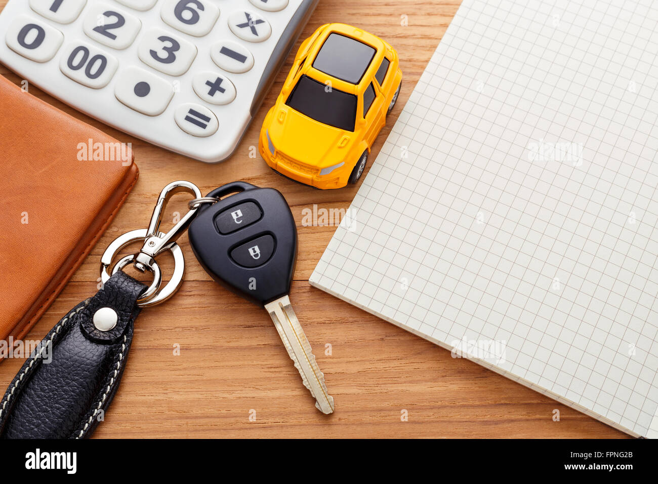 Chiave auto con calcolatrice portatile e pocket money su tavola di legno Foto Stock